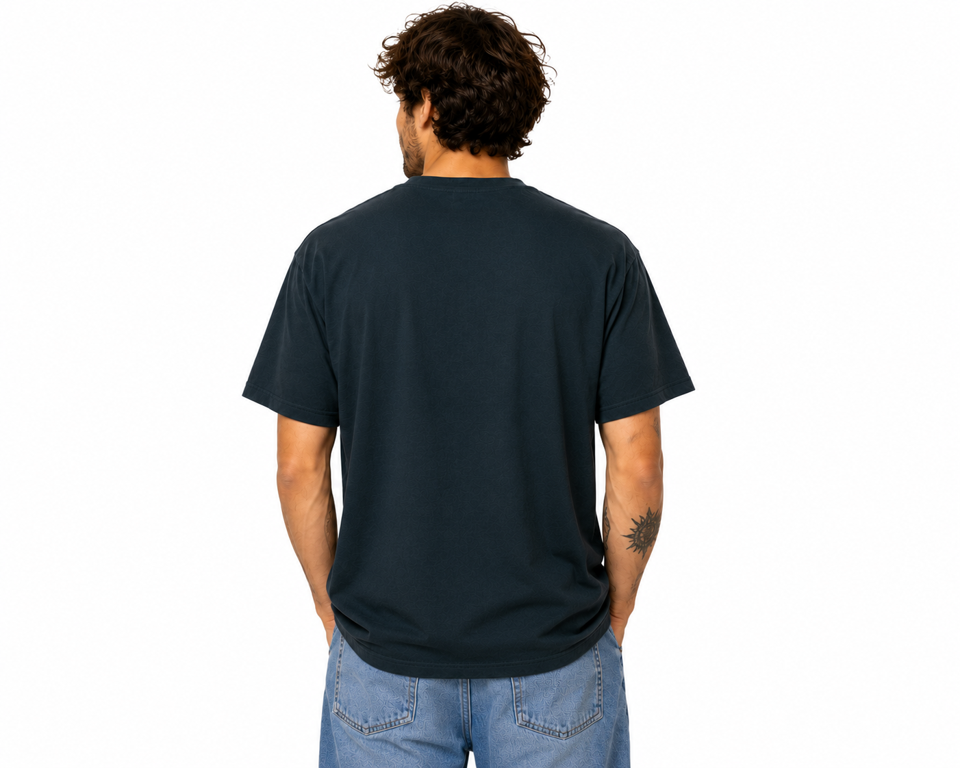 A man viewed from behind wearing a dark navy blue short-sleeve t-shirt and light blue jeans, standing against a plain white background.