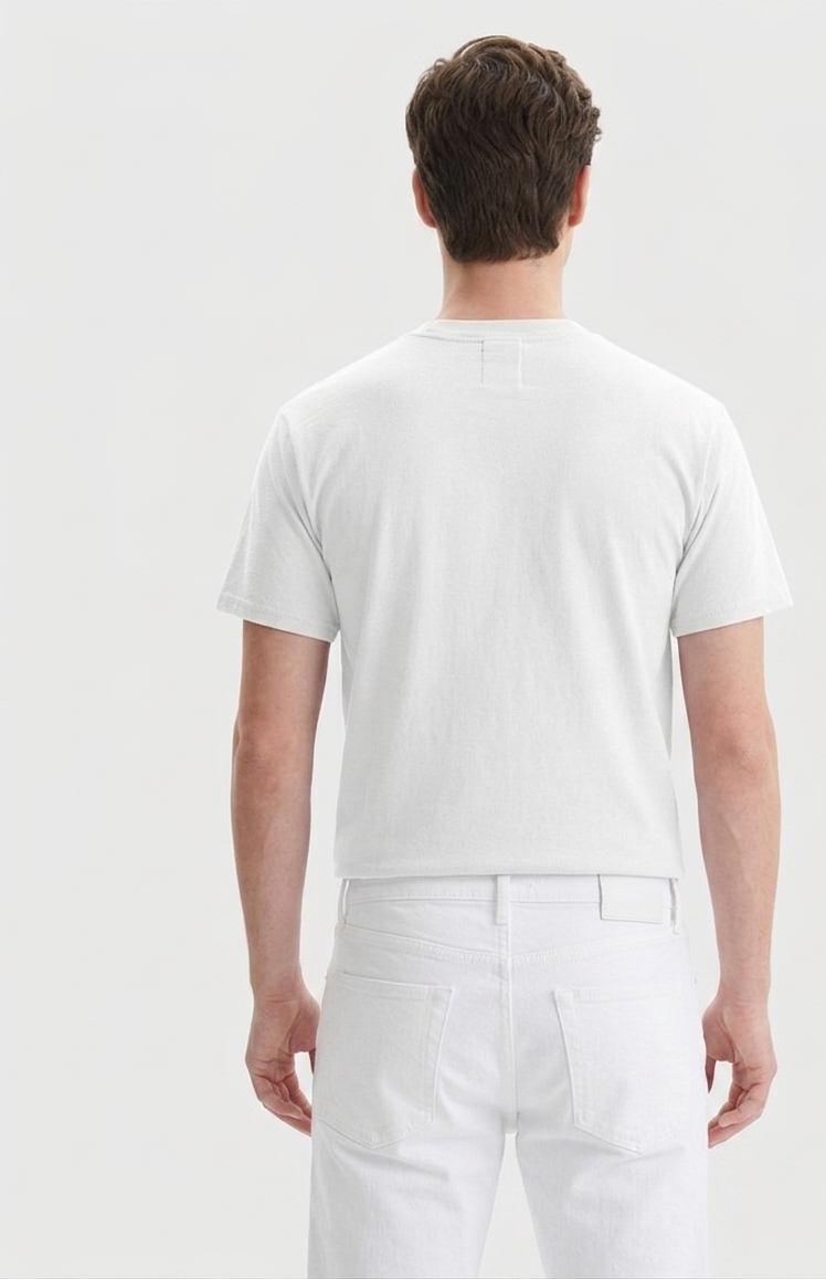 A man viewed from behind wearing a white short-sleeve crewneck t-shirt and white trousers against a light gray studio background.