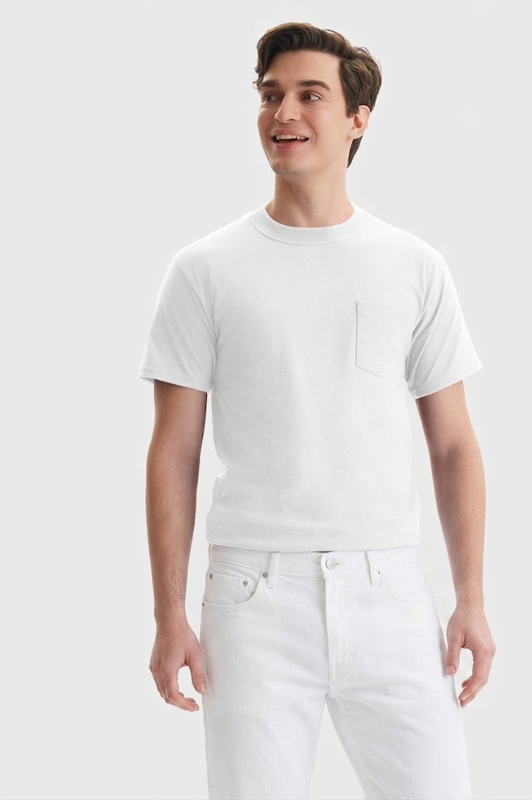 A man wearing a white short-sleeve crewneck t-shirt with a chest pocket and white jeans, standing against a light gray studio background.