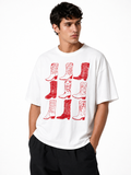 A man wearing a white crewneck t-shirt with a red graphic print of nine cowboy boots, paired with black pants, against a plain white background.