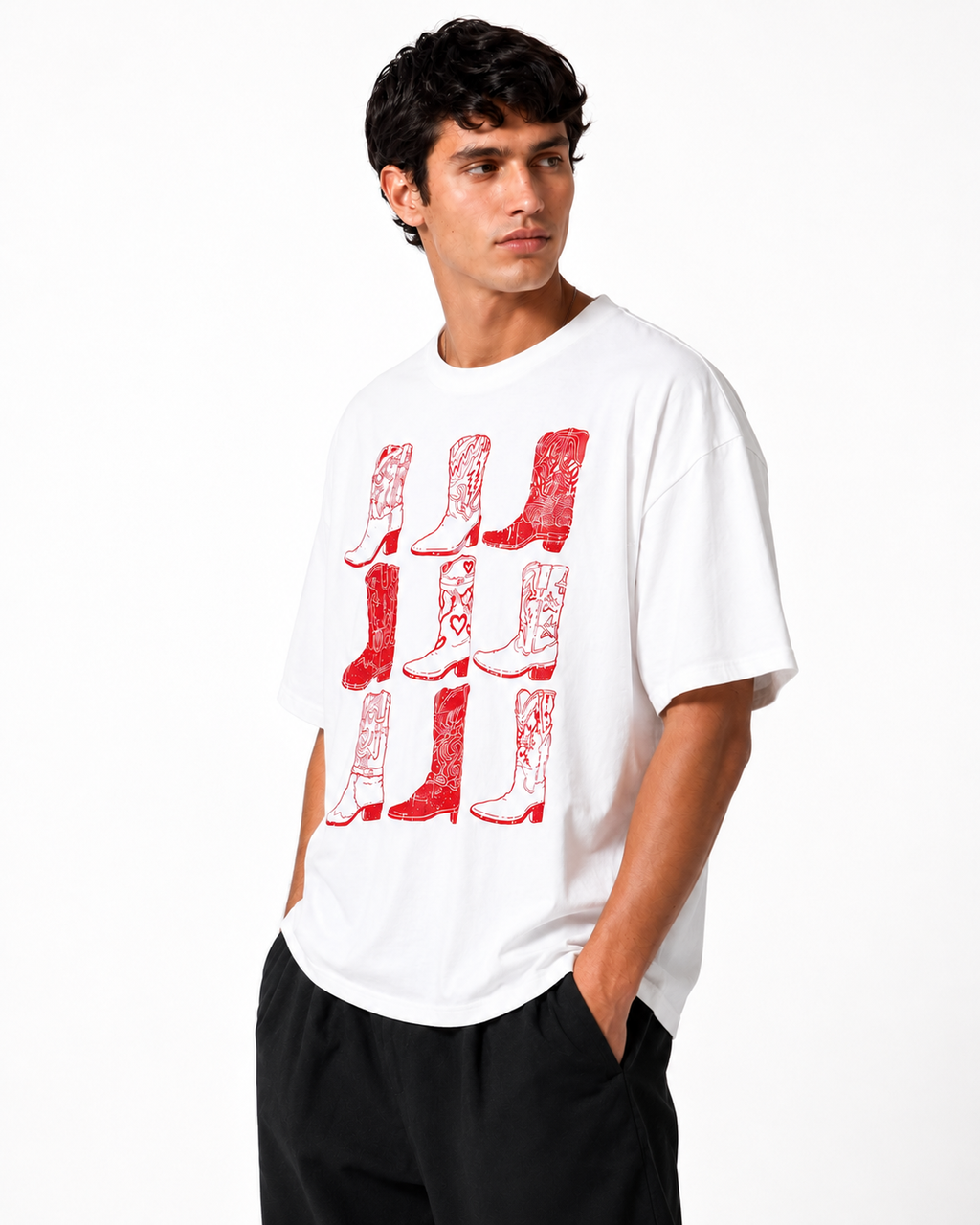 A man wearing a white crewneck t-shirt with a red distressed graphic of cowboy boots, paired with black pants, against a plain white studio background.